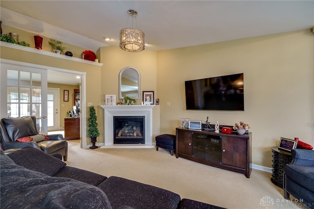 living area with baseboards, a glass covered fireplace, and light colored carpet