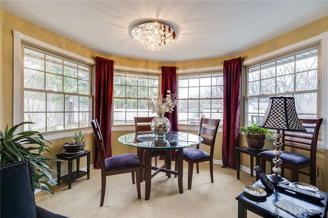 dining area featuring light colored carpet, baseboards, and an inviting chandelier