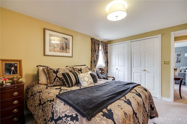 bedroom with carpet floors, two closets, and baseboards