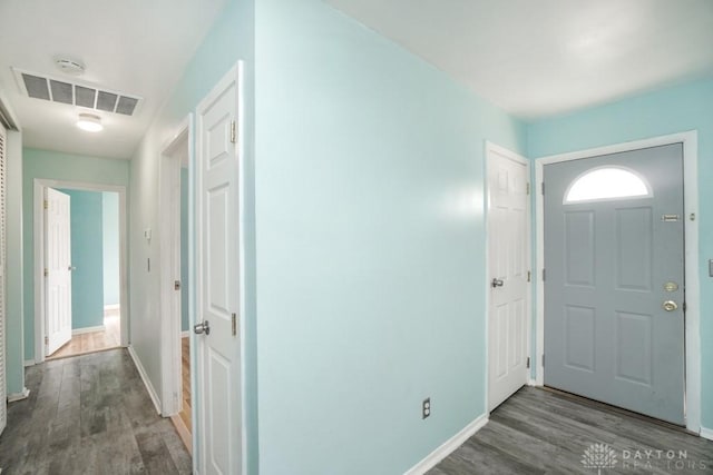 foyer with baseboards, visible vents, and wood finished floors