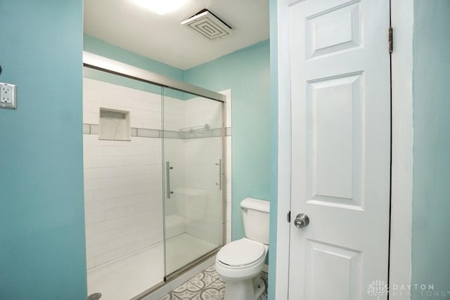 bathroom featuring toilet, a stall shower, and visible vents