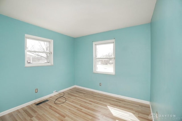 spare room with visible vents, light wood-style flooring, and baseboards