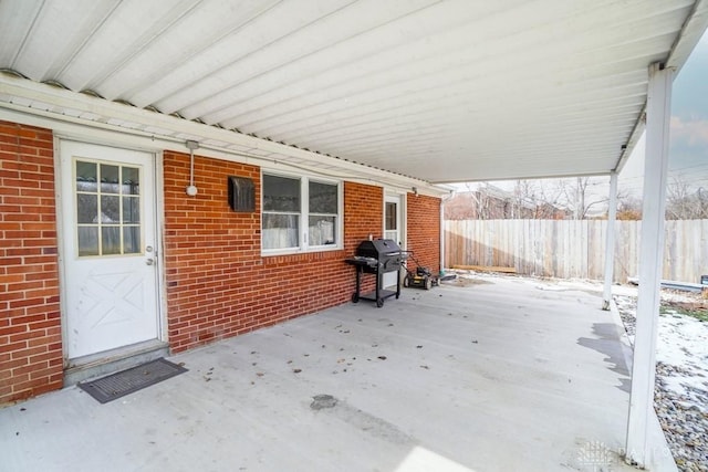 snow covered patio featuring fence and grilling area