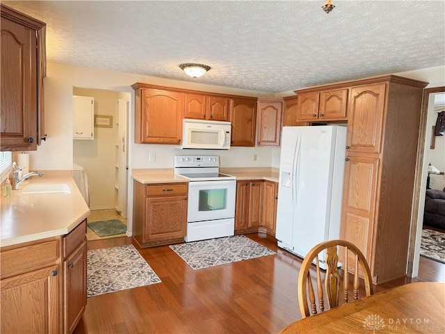 kitchen with white appliances, a sink, light countertops, brown cabinets, and dark wood finished floors