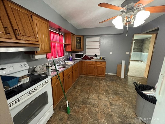 kitchen featuring white appliances, brown cabinetry, a ceiling fan, glass insert cabinets, and a sink