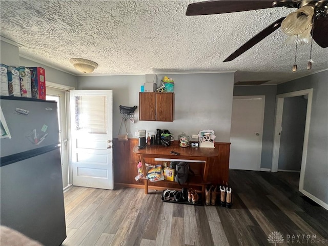 kitchen featuring a textured ceiling, ceiling fan, wood finished floors, baseboards, and freestanding refrigerator