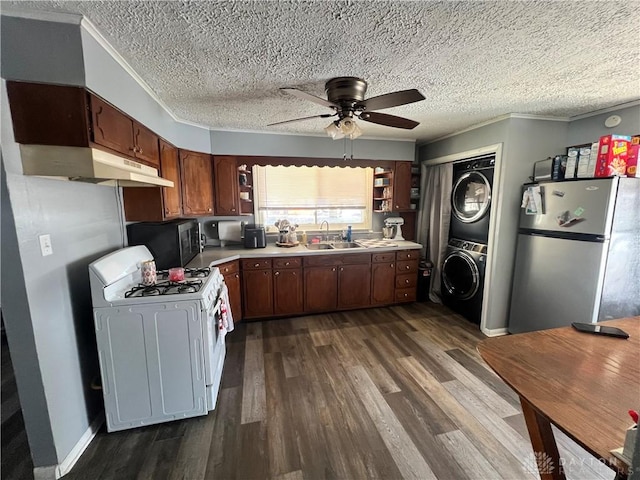 kitchen with appliances with stainless steel finishes, stacked washer / drying machine, light countertops, open shelves, and a sink