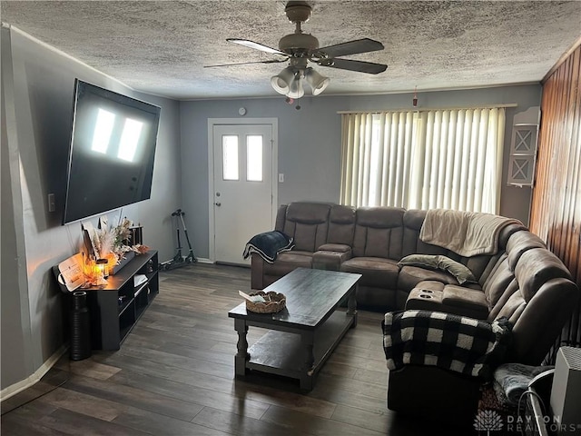 living area with a textured ceiling, ceiling fan, dark wood-type flooring, and baseboards