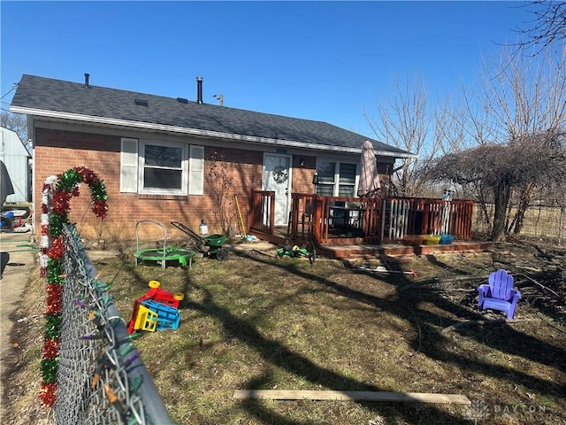 back of house featuring brick siding, fence, a deck, and roof with shingles