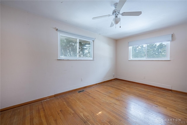 empty room with ceiling fan, light wood-style flooring, visible vents, and baseboards