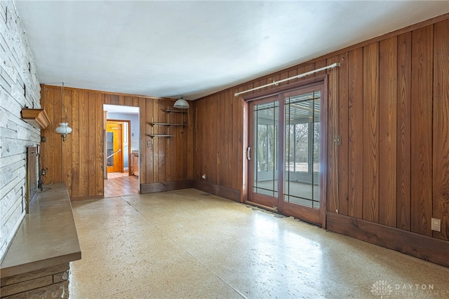 empty room with a fireplace, wood walls, and light floors