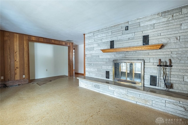 unfurnished living room with a stone fireplace and speckled floor