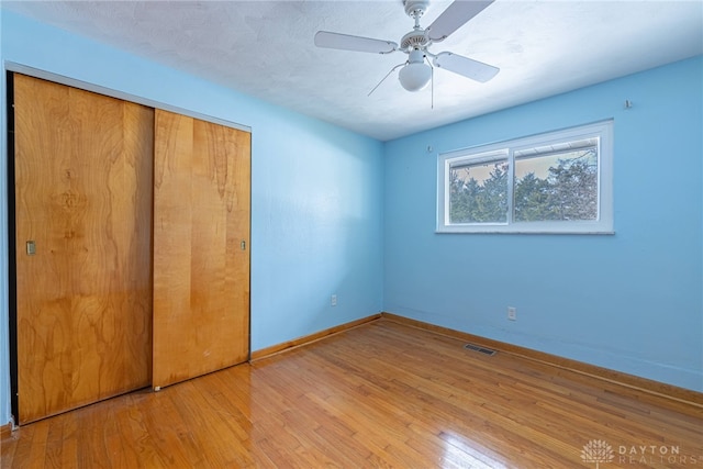 unfurnished bedroom featuring light wood-style floors, baseboards, visible vents, and a closet