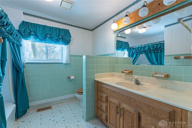 bathroom featuring visible vents, tile walls, toilet, and vanity