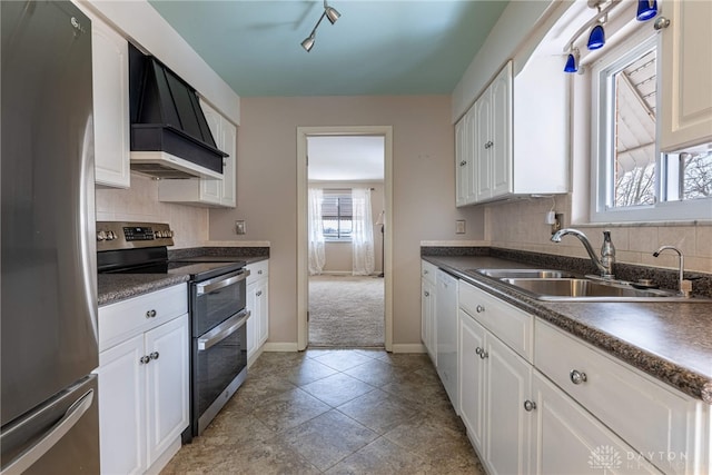 kitchen with a sink, appliances with stainless steel finishes, dark countertops, and custom exhaust hood