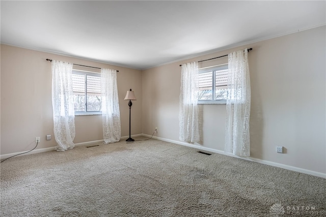 spare room featuring carpet floors, baseboards, visible vents, and a wealth of natural light