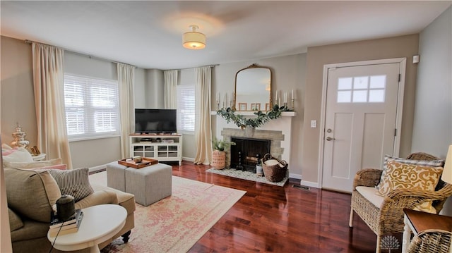 living room with dark wood-style flooring, a fireplace with flush hearth, and baseboards