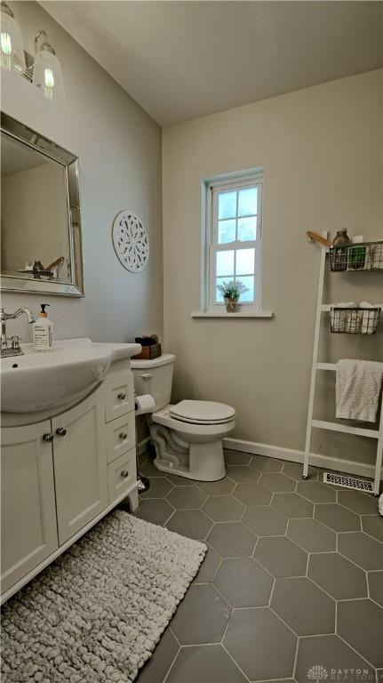 bathroom with tile patterned floors, vanity, toilet, and baseboards