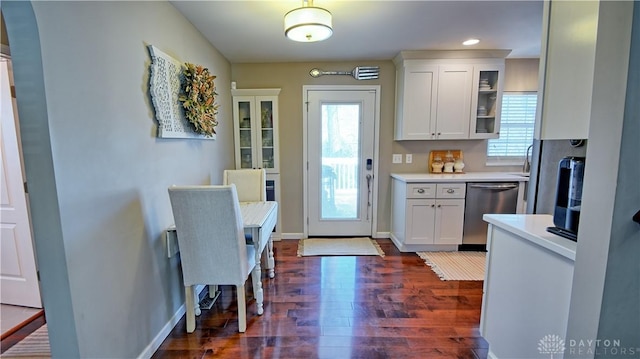 kitchen with light countertops, stainless steel dishwasher, glass insert cabinets, a healthy amount of sunlight, and white cabinetry