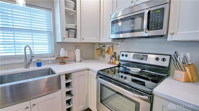 kitchen featuring light countertops, appliances with stainless steel finishes, glass insert cabinets, and white cabinetry