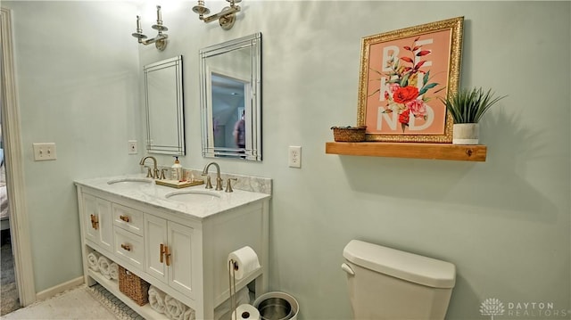 full bath with double vanity, a sink, toilet, and baseboards