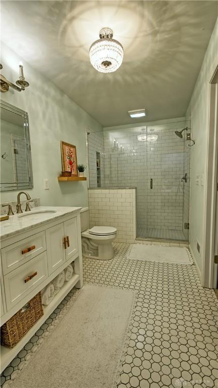 full bath with toilet, a shower stall, vanity, and tile patterned floors