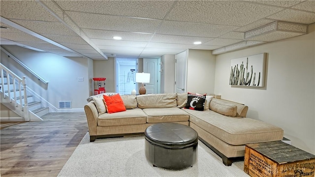 living room with a paneled ceiling, stairs, visible vents, and wood finished floors