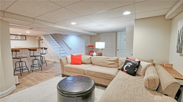 living room with recessed lighting, a paneled ceiling, wood finished floors, baseboards, and stairs