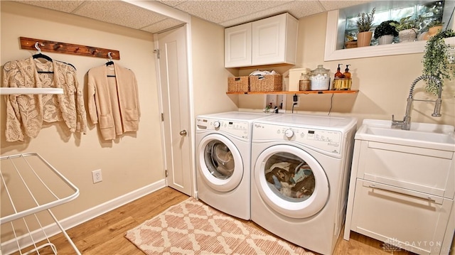 washroom with cabinet space, a sink, light wood-type flooring, independent washer and dryer, and baseboards