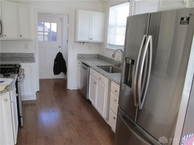 kitchen featuring white cabinets, dark wood-style floors, appliances with stainless steel finishes, light stone countertops, and a sink