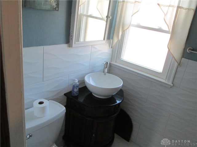 bathroom with toilet, tile walls, and vanity