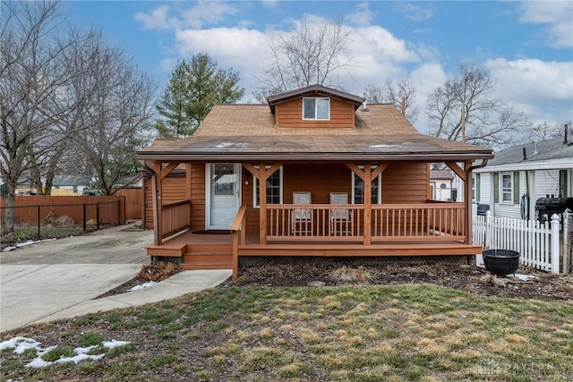 view of front of home with a porch, a front lawn, and fence