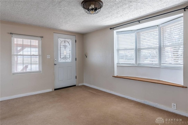 entrance foyer with light carpet, a textured ceiling, and baseboards