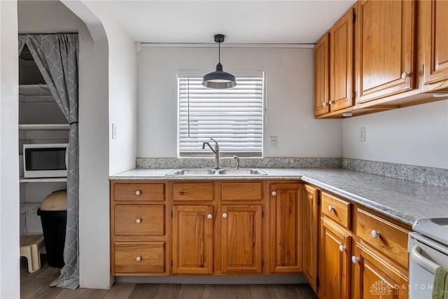 kitchen featuring brown cabinets, light countertops, a sink, and decorative light fixtures