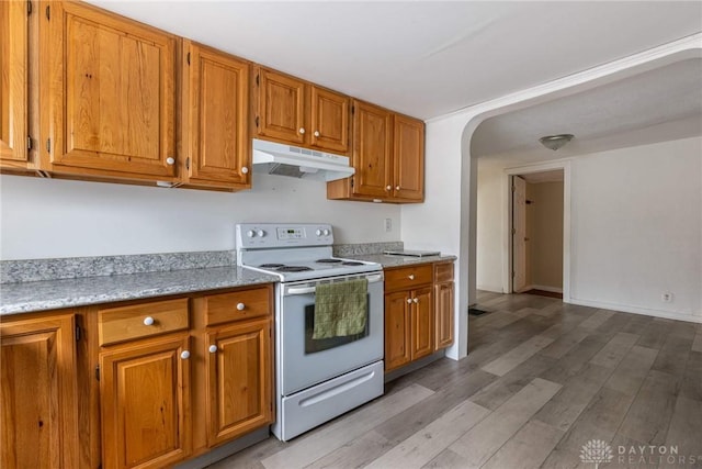 kitchen with brown cabinets, light wood finished floors, light countertops, white electric range, and under cabinet range hood