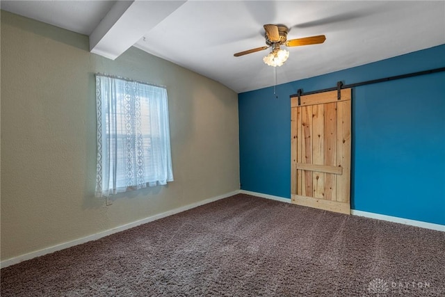 carpeted empty room featuring lofted ceiling with beams, a barn door, baseboards, and ceiling fan