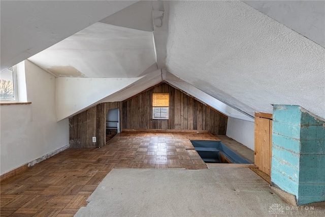 additional living space with vaulted ceiling, wood walls, and a textured ceiling