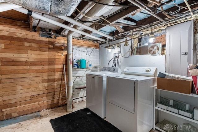 clothes washing area with laundry area, washing machine and clothes dryer, and wooden walls