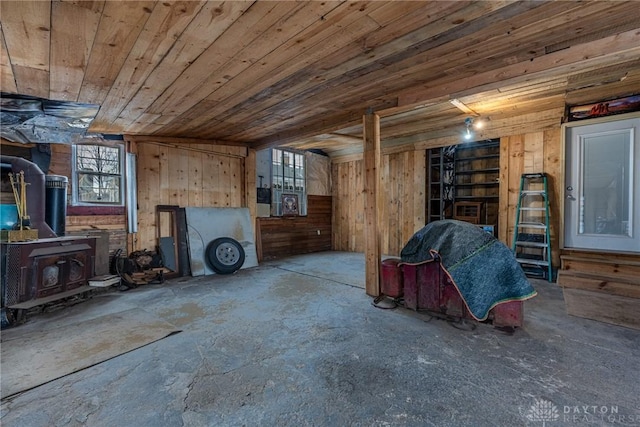 unfurnished living room with wooden ceiling, wood walls, and a wood stove