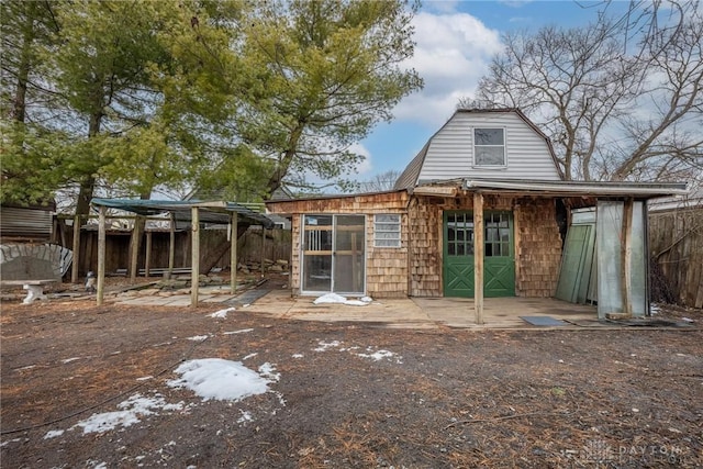 rear view of house with fence and a gambrel roof