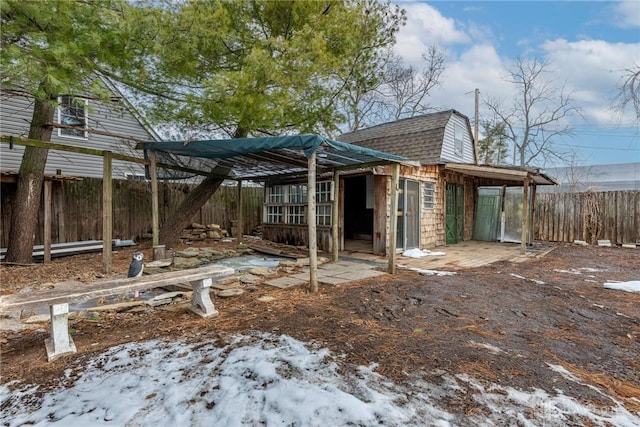 exterior space with roof with shingles, fence, and a gambrel roof