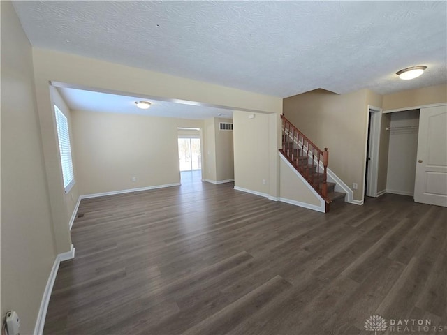 unfurnished living room with dark wood-style floors, stairway, and baseboards