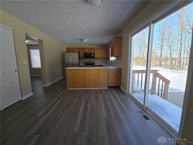 kitchen featuring stainless steel appliances, a sink, visible vents, light countertops, and brown cabinets