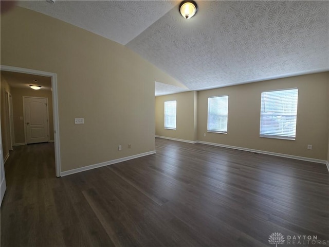 unfurnished room featuring lofted ceiling, dark wood-type flooring, a textured ceiling, and baseboards