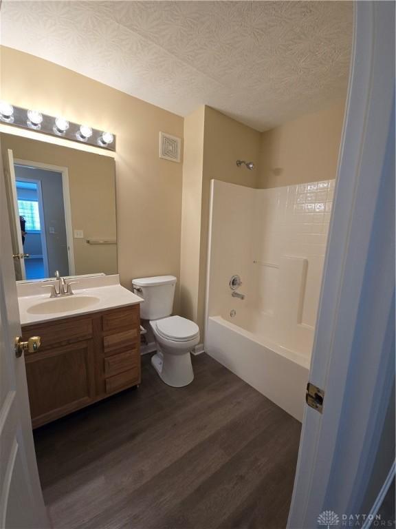 bathroom with visible vents, toilet, wood finished floors, a textured ceiling, and shower / washtub combination