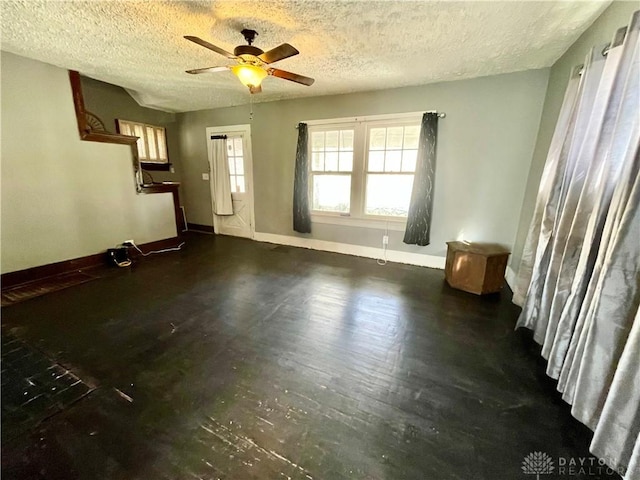 unfurnished living room featuring a textured ceiling, a ceiling fan, and baseboards