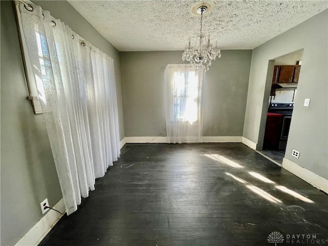 unfurnished dining area featuring dark wood-style flooring, a textured ceiling, and baseboards