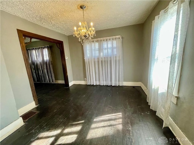 unfurnished dining area with baseboards, visible vents, and dark wood finished floors