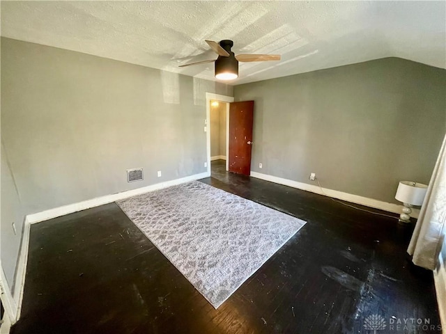 spare room featuring baseboards, visible vents, a ceiling fan, vaulted ceiling, and a textured ceiling