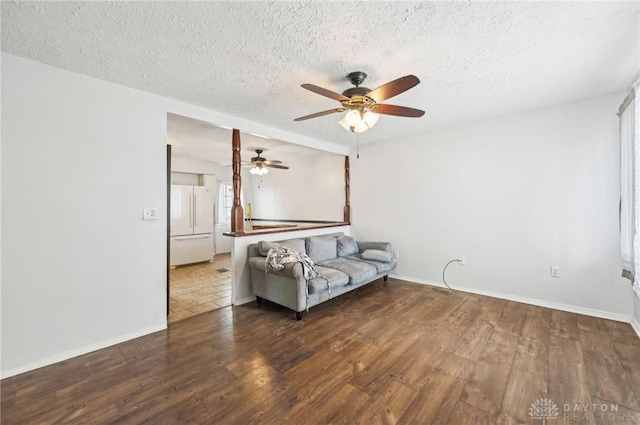 unfurnished living room with dark wood finished floors, a textured ceiling, baseboards, and ceiling fan